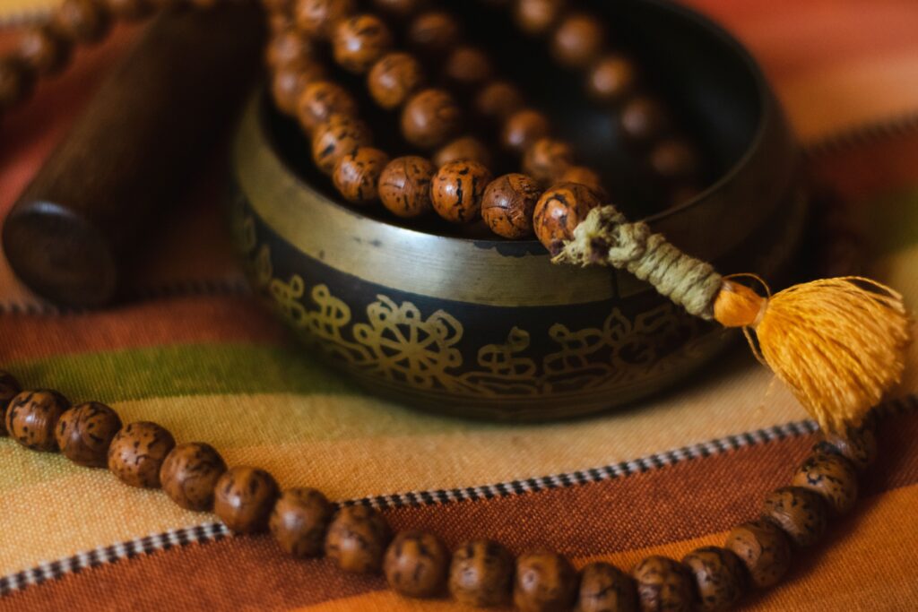Closeup Shot Of A Tibetan Bowl With A Mala On A Striped Cushion